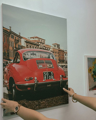 A canvas print of a vintage red car hanged on the white wall.